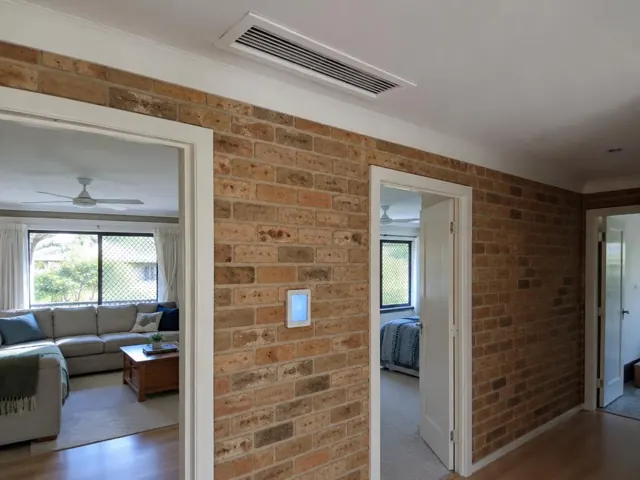 Ceiling ducted air outlet and wall controller on a brick hallway wall in Parkwood